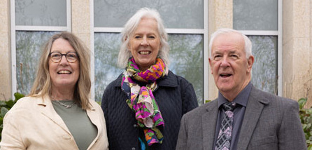 Two women and one man, all retired teachers, smile for a photo.