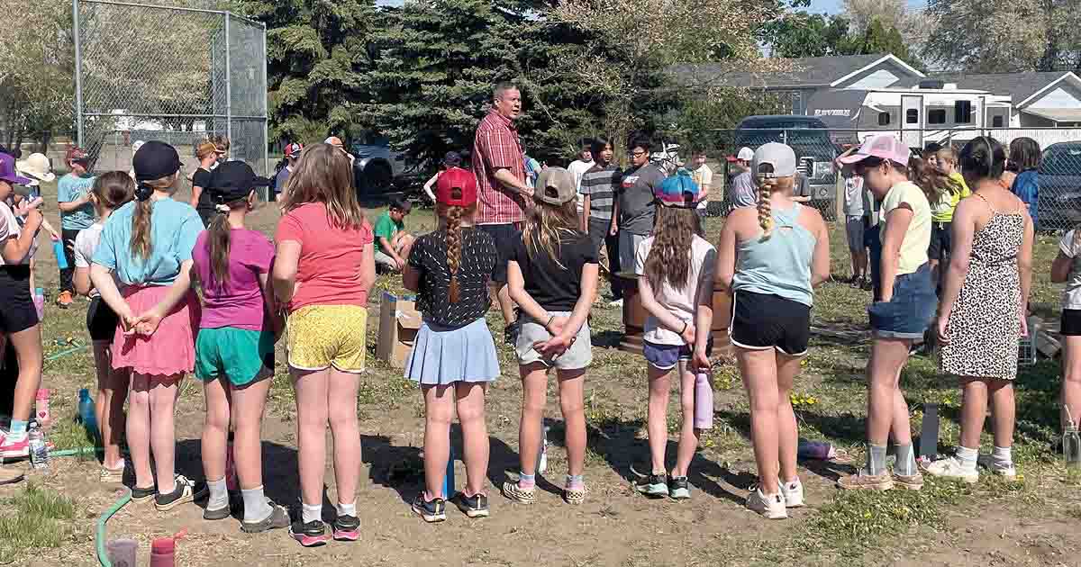 Children stand in a circle as an instructor teaches how to start a fire.