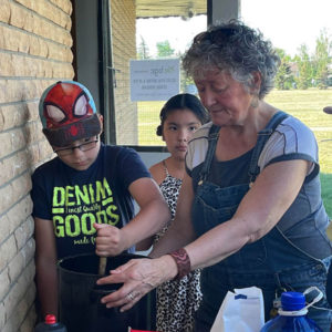 A woman and two children mash berries to make jam.