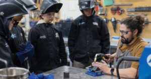 Students watch as a teacher demonstrates welding technique.