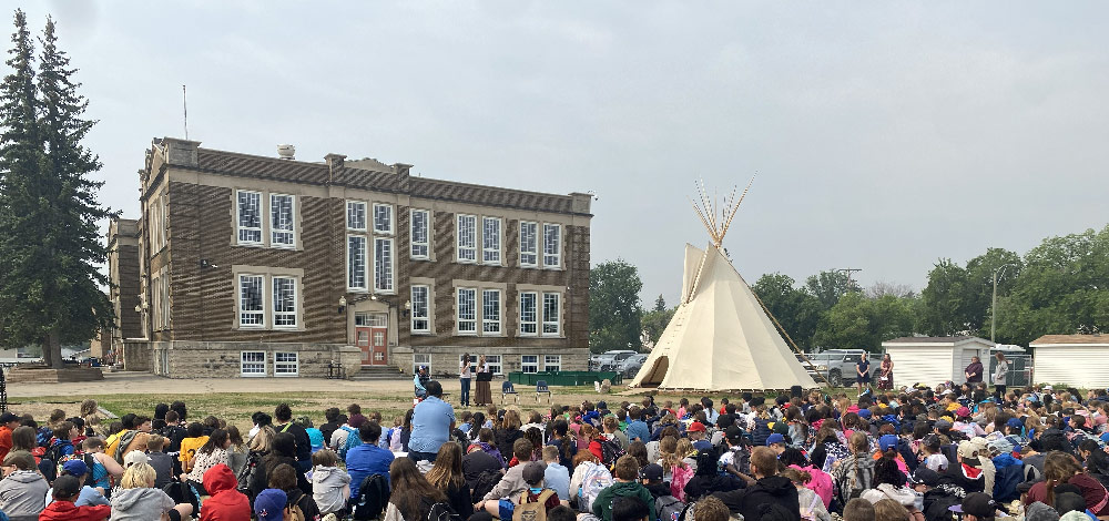 Students sit facing a tipi on the lawn of King George Elementary School in Moose Jaw. Photo supplied